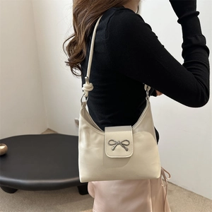 Chic cream leather hobo bag with silver bow accent and knot shoulder strap detail