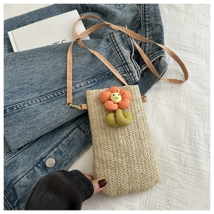Detailed straw woven texture of vertical phone bag with orange smile flower accessory