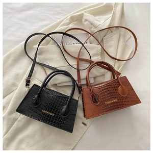 Detail view of black and brown crocodile texture handbags on a white blazer