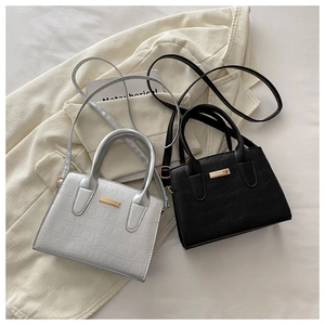 Détail de mini sacs bandoulière argentés et noirs avec texture crocodile et bijoux dorés