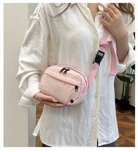 Pale pink nylon crossbody bag worn by model showing casual urban style and size
