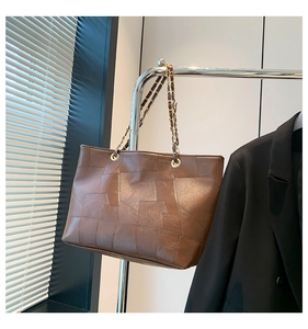 Detail of a large vintage brown PU leather tote bag with geometric patchwork stitching