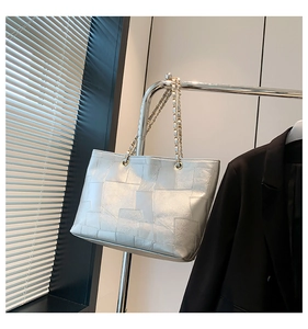 Close-up of metallic silver tote bag with geometric patchwork and double chain straps