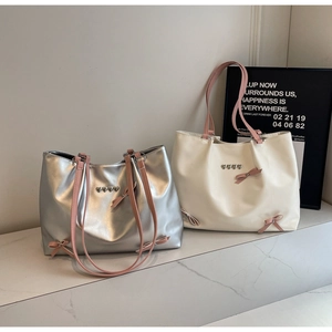 Detail of silver and beige tote bags with pink bows and heart metal ornaments