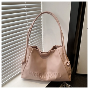 Detail of the pink shoulder bag featuring embossed WGONCZHU lettering and side knot details