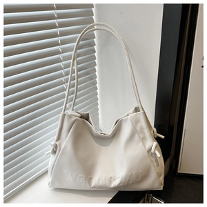 Close-up of white leather shoulder bag featuring embossed text and side knot detail