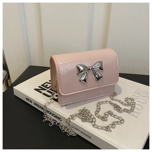 Détail du mini sac carré rose avec fermoir nœud argenté et bandoulière chaîne sur magazine