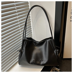 Close-up of black matte leather tote bag featuring subtle pleats and logo embossing