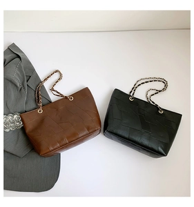 Detail view of large tote bags in brown and black with geometric stitching and chain straps