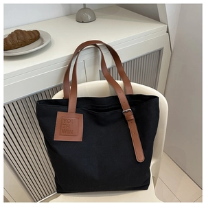 Close-up of black canvas tote bag featuring adjustable brown leather straps and Youth Win logo