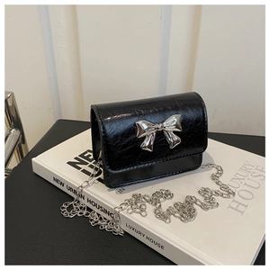 Détail du mini sac bandoulière noir brillant avec gros nœud en métal argenté et chaîne