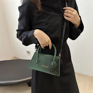 Dark green faux crocodile skin handbag with top handle and gold text fashion detail