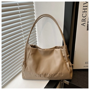Detail of the embossed logo texture and side drawstring on khaki shoulder tote bag