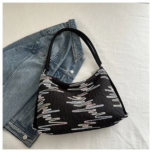 Détail d'un sac cabas noir avec broderie de vagues colorées et bandoulière en cuir