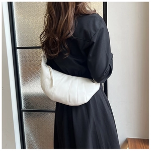Rückansicht eines Models mit weißer plissierter Croissant-Tasche und breitem Trageriemen