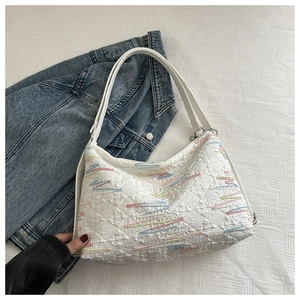 Détail d'un sac cabas blanc matelassé avec broderies colorées sur similicuir de qualité