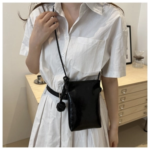 Détail du petit sac bandoulière noir brillant en cuir verni avec nœud sphérique tressé