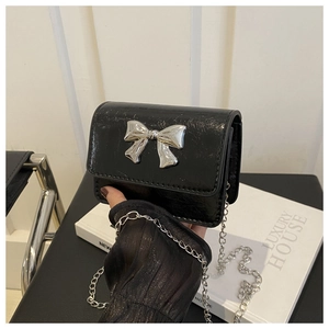Détail d'un sac bandoulière noir en cuir ciré avec un nœud en métal argenté chic