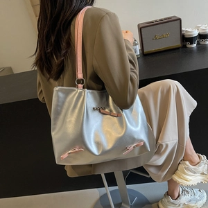 Silver metallic tote bag with pink bow accents and large capacity shown on model
