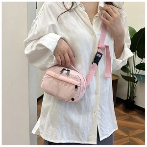 Detailed view of pink nylon crossbody bag with dual zippers and adjustable strap