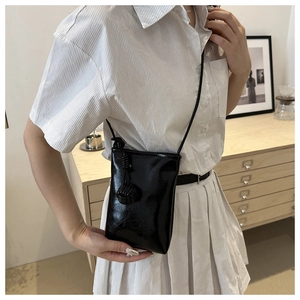 Détail d'un sac à bandoulière noir en cuir brillant avec décoration de nœuds tissés