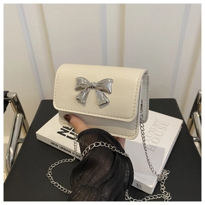 Détail du mini sac blanc crème avec un nœud argenté et une bandoulière en chaîne