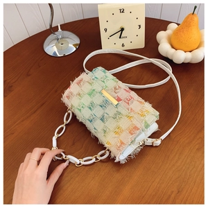 Détail d'un sac bandoulière en tweed coloré avec bords effilochés et chaîne acrylique