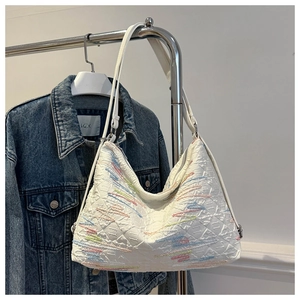 Gros plan d'un sac cabas blanc avec broderies colorées suspendu à un portant