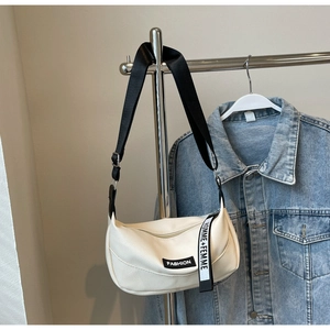 Détail du sac blanc en cuir litchi avec étiquette Fashion et bandoulière contrastée