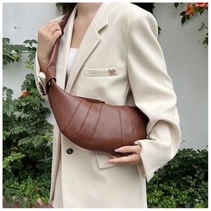 Nahaufnahme der braunen Plisse-Schultertasche mit Knotendetail am Riemen zum Blazer