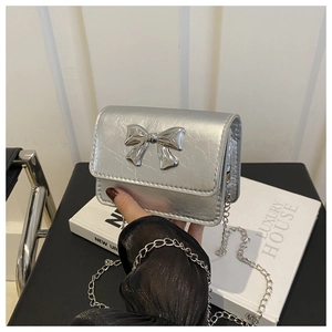 Détail du sac argenté en cuir froissé avec nœud métallique et bandoulière chaîne