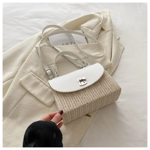 Detail of woven straw handbag featuring a white leather flap and silver twist lock
