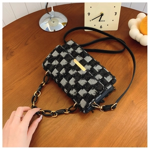 Vue détaillée de la texture en tweed à carreaux noir et blanc avec boucle dorée