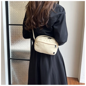 Close-up of lightweight beige nylon crossbody bag with black zipper pocket for daily use