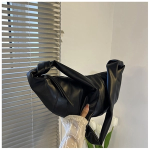 Detail der schwarzen Plissee-Schultertasche mit Knotengriff und vertikalen Steppnähten