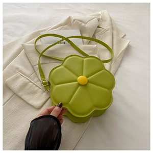Detail of flower-shaped green crossbody bag featuring a yellow center button accent