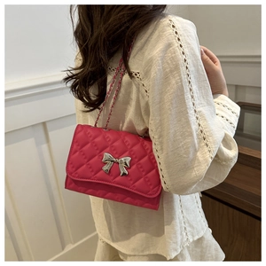 Gros plan du sac matelassé rouge rose avec un nœud en métal argenté et une chaîne