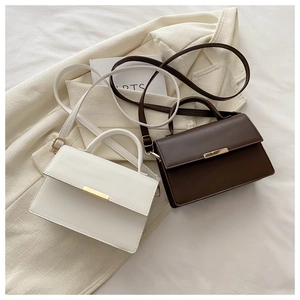 Detail view of cream and brown crossbody bags with gold metal bar magnetic closures