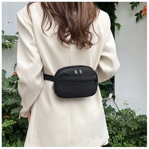 Close-up of a black nylon waist bag worn on a waist with dual metal zippers and adjustable strap