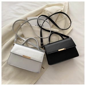 Detail of silver and black leather crossbody bags with golden metal buckle decoration