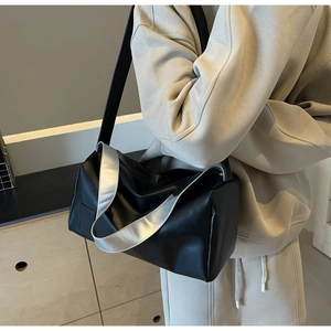 Detail of black matte leather shoulder bag with unique dual straps and silver metal handle