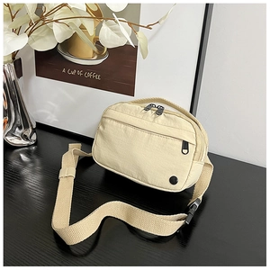 Detail of light beige nylon messenger bag with smooth zippers and adjustable strap