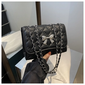 Détail du sac bandoulière noir matelassé avec nœud argenté et bandoulière en chaîne