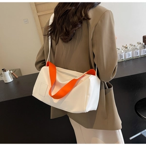 Close-up of a white cylinder sports bag featuring vibrant orange handles and shoulder strap