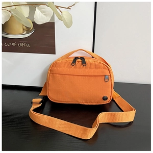 Close-up of bright orange nylon crossbody bag featuring textured grid and front zip pocket
