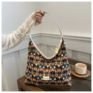Detail of colorful geometric woven pattern and off-white leather strap on a hobo bag
