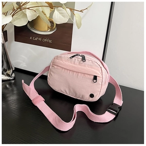 Pink nylon crossbody bag detail with black zippers and adjustable woven strap
