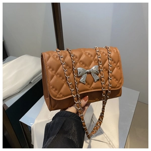 Détail de la texture en cuir marron matelassé et boucle en nœud argenté