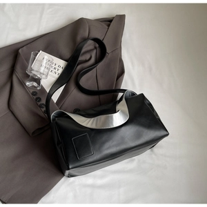 Detail of minimalist black leather crossbody bag with silver metallic edge in urban setting