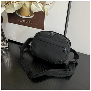 Macro shot of durable black nylon crossbody bag featuring secure zippers and adjustable strap